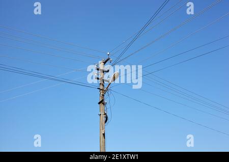 Nahaufnahme der alten Säule an einem Sommertag. Stromlinienpfosten mit Stromkabeln gegen einen klaren blauen Himmel Stockfoto