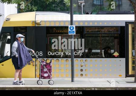 Manchester, Großbritannien - 02 2020. August: Eine Person mit Gesichtsbedeckung wartet auf eine Straßenbahn am St. Peter's Square in Manchester. Stockfoto