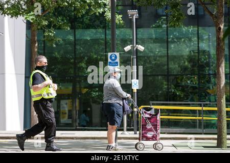 Manchester, Großbritannien - 02 2020. August: Eine Person mit Gesichtsbedeckung wartet auf eine Straßenbahn am St. Peter's Square in Manchester. Stockfoto