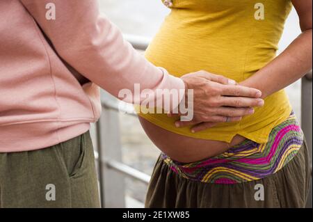 Hand des Mannes auf dem Bauch der schwangeren Dame. Schöne Szene von Eltern erwarten Baby. Zärtlichkeit, Pflege, neues Leben, Gesundheit der Frauen Wellness, Fruchtbarkeit Konzepte Stockfoto