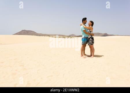 Romantisches Paar, das sich in der leeren Wüste im Corralejo Natural Park anschaut. Mann und Frau posieren auf Sanddünen auf Fuerteventura, Spanien Stockfoto