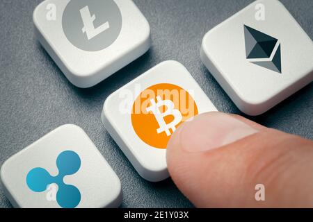 Finger drücken Cursor-Taste mit Bitcoin-Symbol. ethereum, Welligkeit und Litecoin-Logos auf anderen Cursor-Tasten auf der Tastatur. Cryprocurrency-Konzept Stockfoto