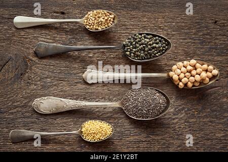Hirse, Chia, Kichererbsen, Buchweizen und Linsen auf fünf Jahrgangslöffeln, Draufsicht Stockfoto
