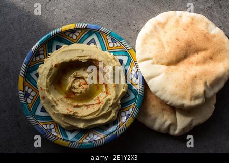 Leckerer Hummus auf buntem Teller. Foto der traditionellen Küche Israels von oben. Ausgewogene Ernährung Konzept. Klassischer israelischer Hummus. Stockfoto