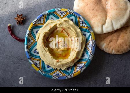 Leckerer Hummus auf buntem Teller. Foto der traditionellen Küche Israels von oben. Ausgewogene Ernährung Konzept. Klassischer israelischer Hummus. Stockfoto