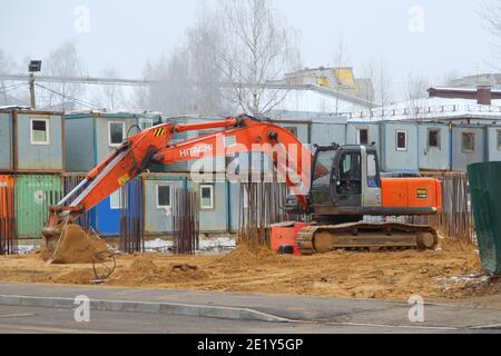 15.11.2020. Russland, Syktywkar. Ein großer orangefarbener Bagger hitachi auf breiten Eisenbahnen steht auf einer Baustelle auf dem Sand vor der Kulisse Stockfoto