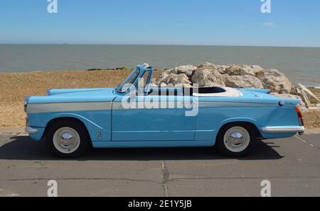 Classic Light Blue Triumph Herald offener Wagen, der an der Strandpromenade geparkt ist. Stockfoto