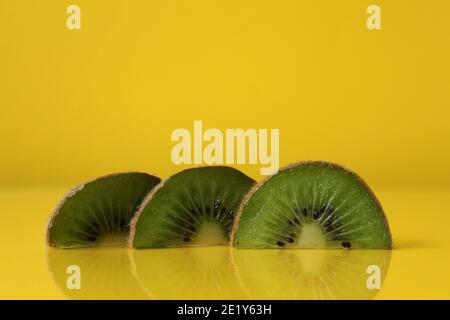 Drei Scheiben Kiwi Hälften liegen in einer Reihe auf Trend iluminaited gelb mit einer Kopie der Platz für Text. Stockfoto