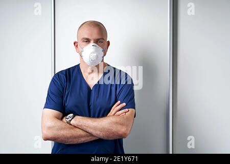 Erfahrene männliche Masseur Masseur in seinem medizinischen Büro stehend Durch einen Massageliegen tragen professionelle Uniform und Einweg-Standard N95 Stockfoto