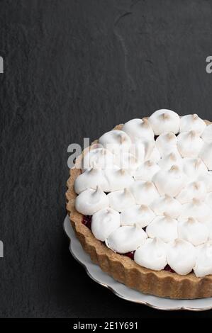 Meringue bedeckt Beerentorte Torte auf schwarzem Stein Hintergrund Stockfoto