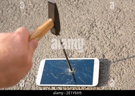 Hammer zerschlägt den Bildschirm eines Smartphones Stockfoto