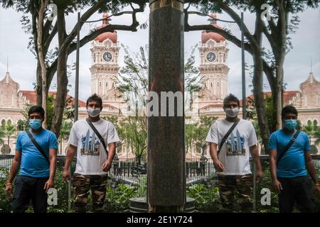 Kuala Lumpur, Malaysia. Januar 2021. Reflexion von Männern, die Gesichtsmasken tragen, als Vorsichtsmaßnahme gegen die Verbreitung von Covid-19, die auf der Straße in Kuala Lumpur gehen. Kredit: Faris Hadziq/SOPA Images/ZUMA Wire/Alamy Live Nachrichten Stockfoto