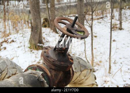 Alte beschädigte und rostige Eisenölrohr Ventilrad. Metall-, Pipeline- und Mechanikkonzept. Ein altes Eisenventil an einer Gasleitung. Ein Ventil zum Abdecken des Rohres mit einem runden Griff. Stockfoto