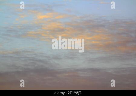 Wolken am Himmel werden von unten durch das rote Licht der Sonne beleuchtet. Sonnenuntergang oder Sonnenaufgang in der Dämmerung. Stockfoto