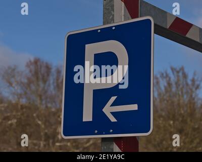 Nahaufnahme von blauem Parkschild mit weißem Buchstaben und Pfeil-Symbol (links) am Metalleingang des Parkhauses in Sigmaringen, Deutschland. Stockfoto