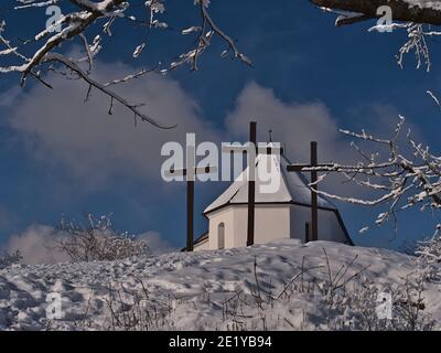 Flachwinkelansicht des Kornbühlbergs, Schwäbische Alb, Deutschland im Winter mit historischer Kapelle Salmendinger Kapelle und drei christlichen Kreuzen davor. Stockfoto