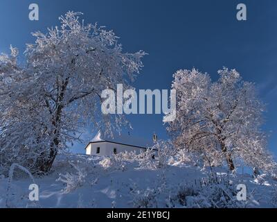 Flachwinkelansicht der Gipfel des Kornbühlhügels bei Burladingen, Schwäbische Alb, Deutschland mit verschneiten historischen Kapelle Salmendinger Kapelle im Winter. Stockfoto