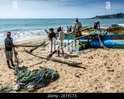 TANGALA, SRI LANKA - 15. März 2019: Asiatische Fischer, die Netze für die Fischerei am Sandstrand vorbereiten. Stockfoto