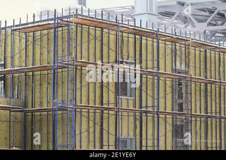 Gerüst in der Nähe der Betonwand eines Gebäudes im Bau. Bauindustrie Entwicklungskonzept, neue Wohnungen, Wiederaufbau, Restaurierung Stockfoto