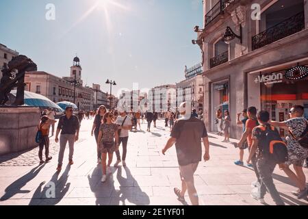2019, Madrid, Spanien. Touristen in der Sonne am Puerta del Sol Platz in Madrid, Spanien. Foto im Vintage-Stil mit Hintergrundbeleuchtung im Orange- und Teal-Look. Stockfoto