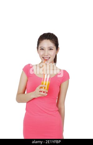 Junge Frau in rosa Kleid trinken ein Glas Orange Für Fotos in hoher Qualität Stockfoto
