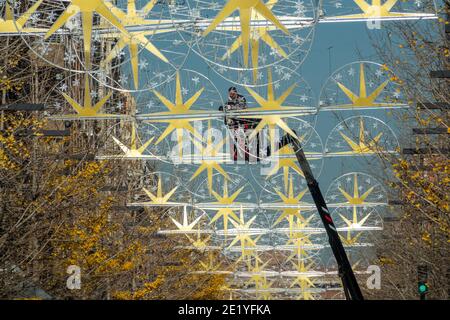 Arbeiten unter den Sternen: Mann auf einem Kran, der Weihnachtsdekorationen auf einer Straße in Granada repariert Stockfoto