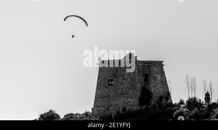 Silhouette eines Gleitschirms, der über dem mittelalterlichen Turm von fliegt Tamaray in Almuñécar (Spanien) Stockfoto