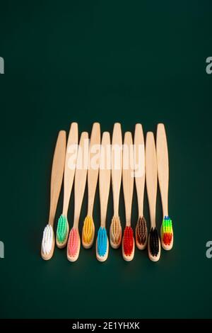 Ein Set umweltfreundlicher antibakterieller Zahnbürsten aus Bambusholz auf dunkelgrünem Hintergrund. Umwelttrends. Stockfoto