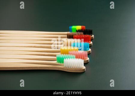 Ein Set umweltfreundlicher antibakterieller Zahnbürsten aus Bambusholz auf dunkelgrünem Hintergrund. Umwelttrends. Stockfoto