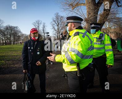 Ein Protestler, der eine Baseballmütze „Make Britain Great Again“ trägt, wird von der Polizei im Clapham Common Park während der Anti-Lockdown-Demonstration befragt. Stockfoto