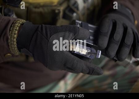 Airsoft Spieler tragen Schutzhandschuhe lädt Bälle in Maschinengewehr Magazin Stockfoto