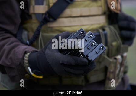 Airsoft Player in Schutzhandschuhen hält Magazine für eine Maschine Pistole in der Hand Stockfoto