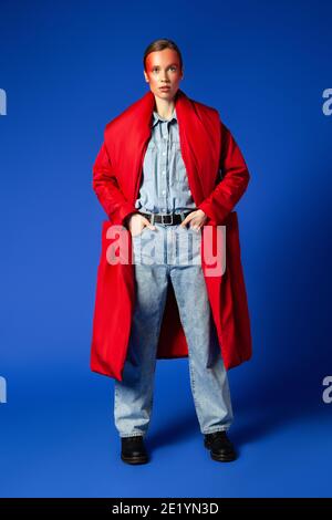 Selbstbewusstes weibliches Modell in baggy Kleidung vor blauem Hintergrund Stockfoto