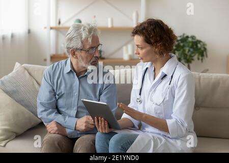 Fachkundiger Arzt, der dem alten Patienten die Testergebnisse auf der Tablette zeigt. Stockfoto