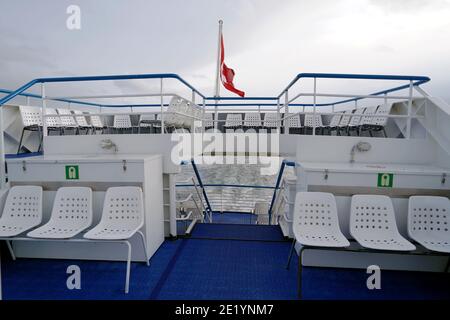 Stamm einer touristischen Fähre auf dem Zürichsee in der Schweiz. Weiße Plastikstühle sind auf drei Decks angeordnet und es gibt die Schweizer Bundesflagge. Stockfoto