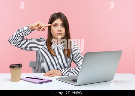 Verärgert Frau Büroangestellte zeigt dumme Geste mit Finger Blick auf die Kamera mit unzufrieden müde Ausdruck, sitzen am Arbeitsplatz mit Laptop. Ind Stockfoto