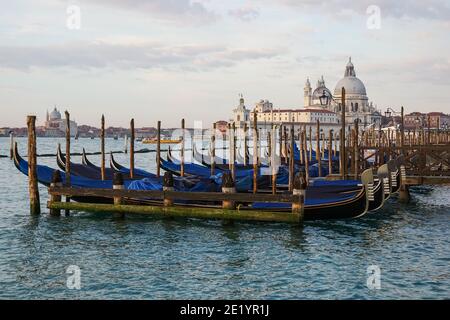 Venezianische Gondel bei Sonnenaufgang, Gondeln in Venedig mit Santa Maria della Salute Basilika im Hintergrund, Italien Stockfoto