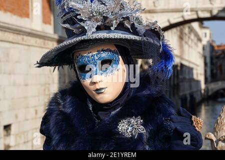 Frau in traditionell dekoriertem Kostüm mit Hut und bemalter Maske während des Karnevals in Venedig, Italien Stockfoto