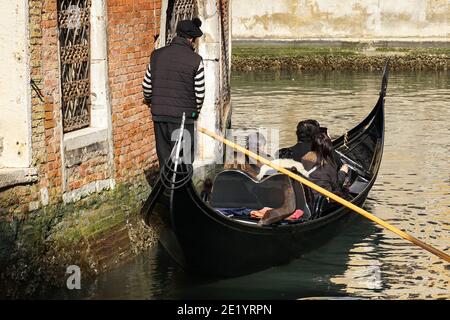 Gondoliere auf der traditionellen venezianischen Gondel mit Touristen auf dem Kanal in Venedig, Italien Stockfoto