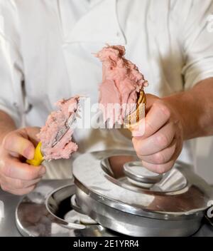 Hände des Eiscremes, der Erdbeereis schaufelt In den Waffelkegel Stockfoto