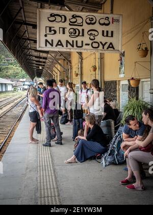 NANU-OYA, SRI LANKA - 13. März 2019: Junge kaukasische Touristen warten auf den Zug am Bahnhof. Vertikale Aufnahme. Stockfoto