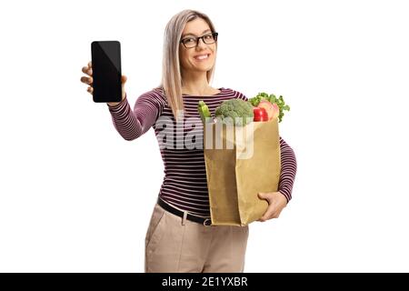 Junge Frau mit einem Lebensmittelbeutel zeigt ein Smartphone isoliert Auf weißem Hintergrund Stockfoto