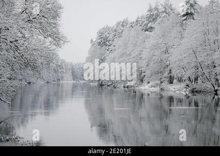 Winterlandschaft von Bäumen am Rande des Flusses. Eiskalt kleiner Fluss. Banken mit Bäumen bedeckt mit Schnee. Riesige Schneeverwehungen liegen auf der Bank der s Stockfoto