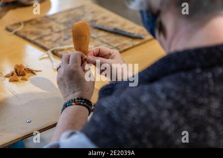 Nahaufnahme von oben einer älteren Frau mit covid schützende Gesichtsmaske arbeiten auf dem Kopf eines Trommelstock während einer einheimischen Trommel-Workshop. Stockfoto