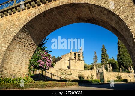 Vouzela Mutterkirche umrahmt vom Bogen der Eisenbahnbrücke in Vouzela, Portugal, an einem sonnigen Tag. Stockfoto