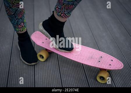 Nahaufnahme des Fußes des Mädchens in schwarzen Sneakers reiten Auf pinkem Penny Skateboard Stockfoto