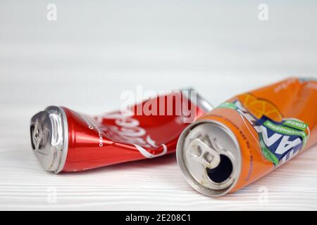 CHARKOW, UKRAINE - 8. DEZEMBER 2020: Zerknitterte Aluminiumdosen von Coca Cola und Fanta Softdrinks auf weißem Holztisch. Zwei beschädigte und gebrauchte Blechdosen Stockfoto