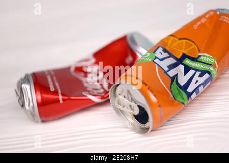 CHARKOW, UKRAINE - 8. DEZEMBER 2020: Zerknitterte Aluminiumdosen von Coca Cola und Fanta Softdrinks auf weißem Holztisch. Zwei beschädigte und gebrauchte Blechdosen Stockfoto