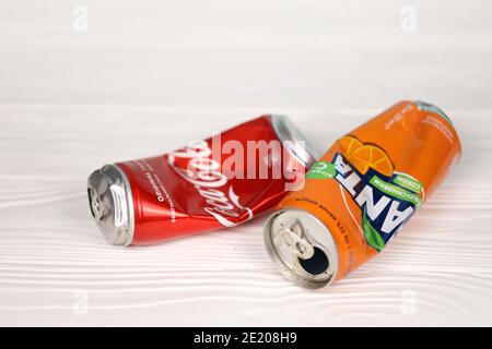CHARKOW, UKRAINE - 8. DEZEMBER 2020: Zerknitterte Aluminiumdosen von Coca Cola und Fanta Softdrinks auf weißem Holztisch. Zwei beschädigte und gebrauchte Blechdosen Stockfoto