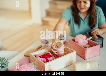 Frau Vorbereitung rosa gefärbte herzförmige Geschenk-Boxen mit Bio Naturkosmetik der Körperpflege Stockfoto